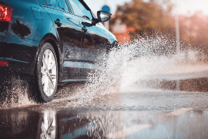 Car driving through large water puddle.