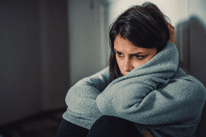 Woman sitting in a dark corner suffering from a mental illness.
