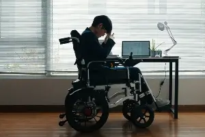 very young man in wheelchair sitting in the shadows with head on his hand