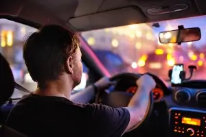 sitting in a car behind a male driver at night