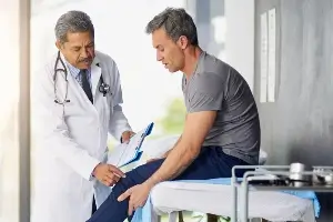 doctor examining young male patient's knee