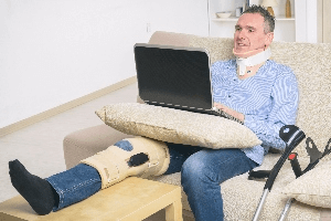 Injured man on sofa using computer