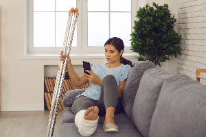 injured young woman with cast using phone